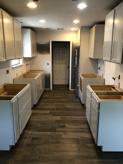Remodeled kitchen with island, white cabinets, and wood-look floor