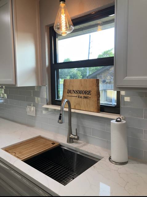 Remodeled kitchen with quartz counters, new sink and faucet, and a Dunsmore sign on the windowsill