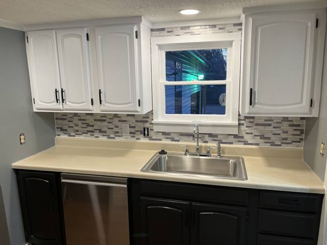 Renovated kitchen with white upper cabinets, dark lowers, and mosaic backsplash