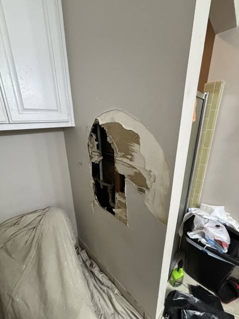 Bathroom wall before: drywall cut out for the repair