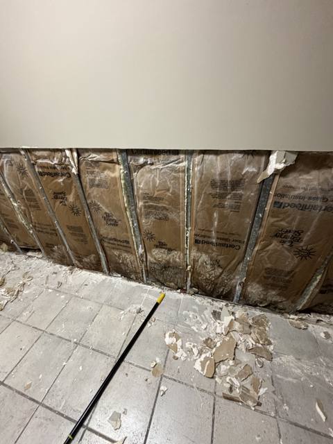 Commercial wall before: opened with insulation exposed